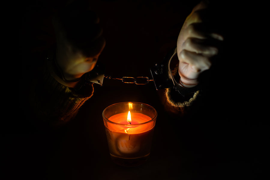 Couple in handcuffs holding a candle, representing passion and intimacy in Lubricants, Waxes, Candles & Toy Cleaners.