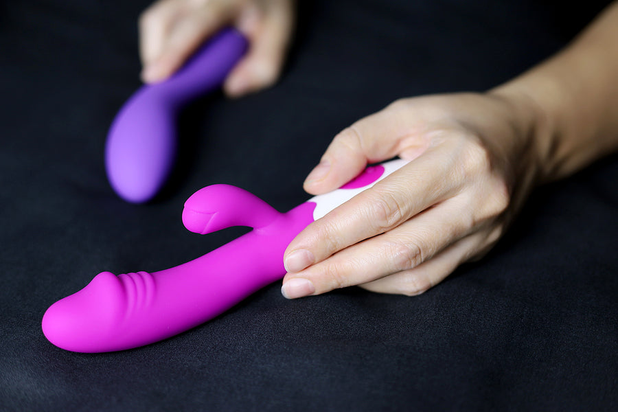 For Her: Close-up of a hand holding a purple vibrator, showcasing intimate essentials for her.