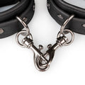Adjustable black handcuffs with metal clip fasteners and chain for bondage play.