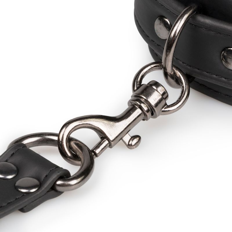 Close-up of a metal clasp on a faux leather hogtie with rivets, showcasing its sturdy design for bondage play.