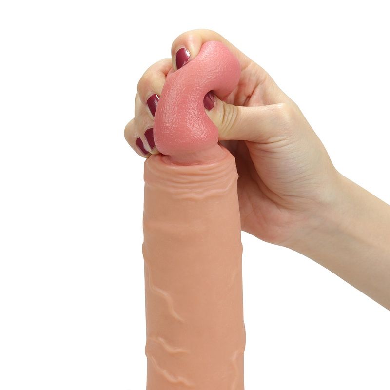 Close-up of a hand squeezing a realistic hollow strap on dildo to showcase its lifelike texture and softness.