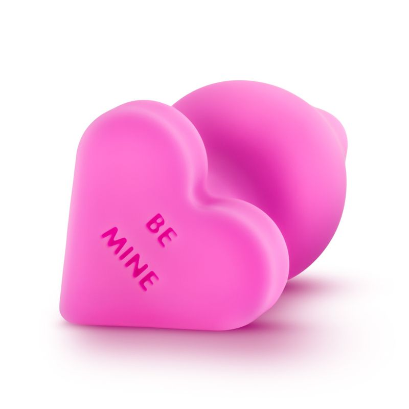Naughty candy heart plugs in pink silicone with the text 'BE MINE' for playful and fun intimacy.