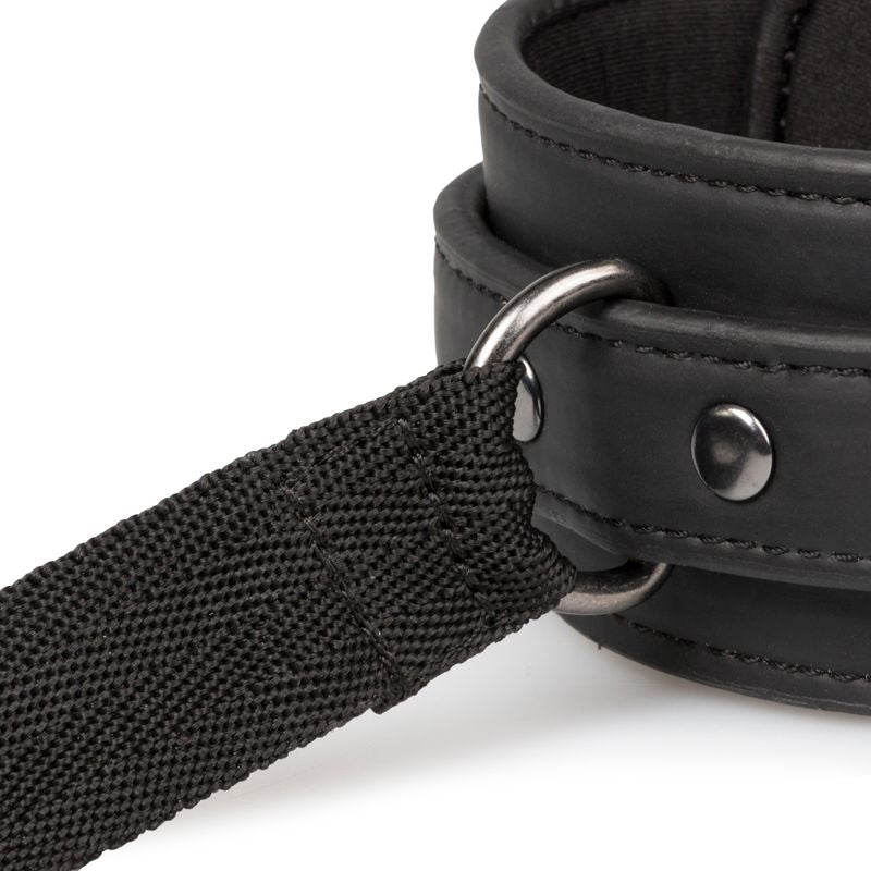 Close-up of a strap from the beginners bondage kit featuring black leather handcuff and fabric handle.