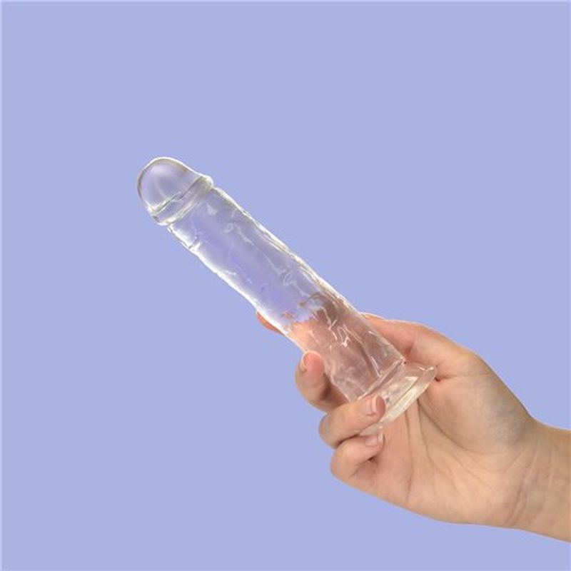 7 inch crystal dildo held by hand against a soft blue background showcasing its clear design and suction base.