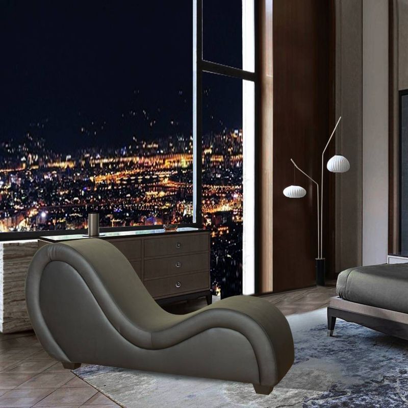 Kama Sutra Mebon Chaise Love Lounge Black elegantly placed in a modern room with a stunning city view at night.