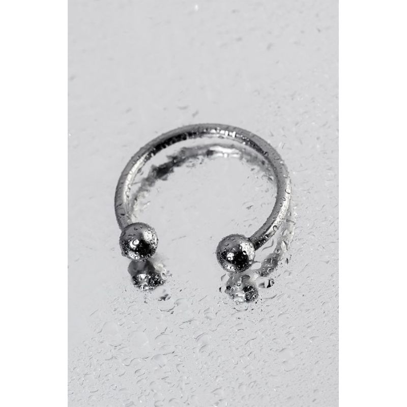30mm metal penis erection ring on a wet surface, featuring an open design and stimulating balls for arousal.
