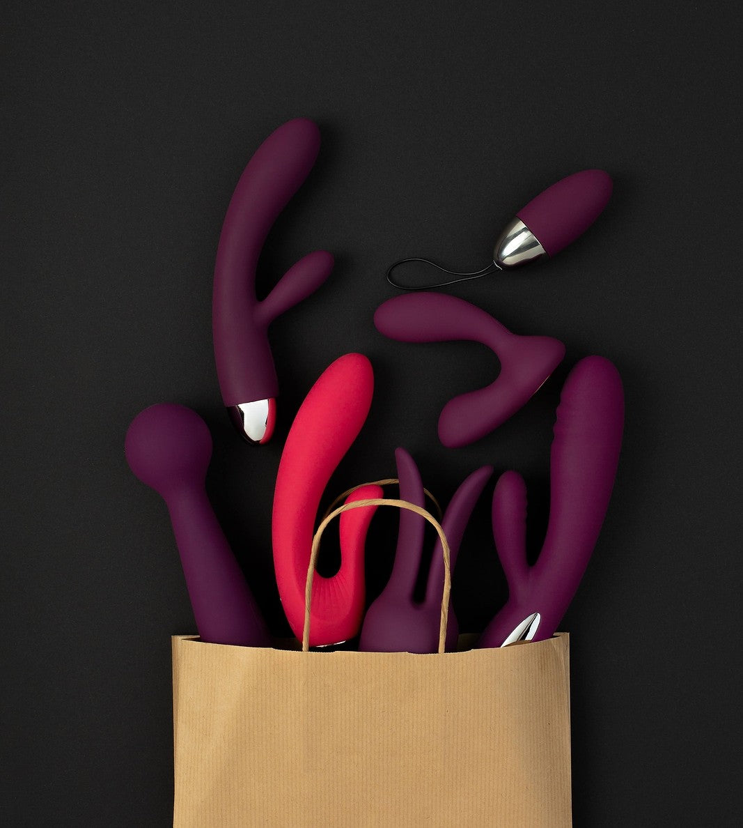 Bag filled with elegant purple and red intimate vibrators and toys for her intimate essentials.