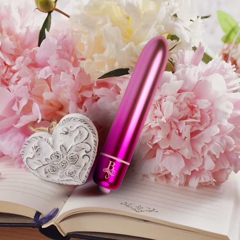 Boudoir Courtesan waterproof bullet vibrator among pink peonies on a decorative notebook.