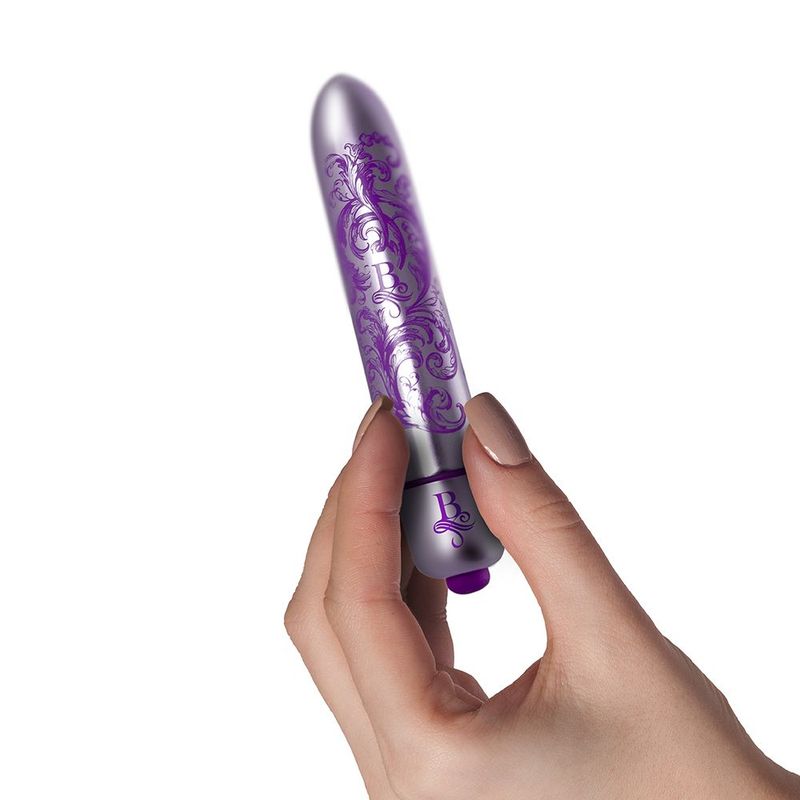 Discreet waterproof bullet vibrator held by a hand, featuring elegant purple designs and sleek finish.