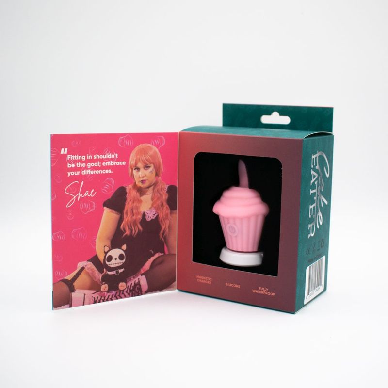Cake Eater Clit Flicker Stimulator Pink packaging next to promotional card featuring model.