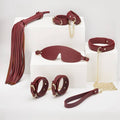 8 Pc Deluxe Bondage Play Kit featuring burgundy faux leather pieces and gold metal trim for erotic play.