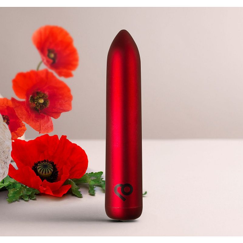 Poppy Red Rechargeable Bullet Vibrator next to vibrant poppy flowers, showcasing elegance and compact design.