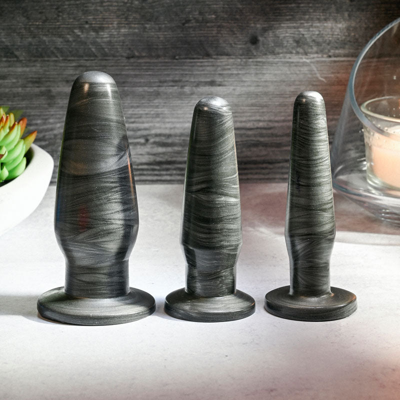 Adam & Eve ANAL ROCKETS TRAINER SET -  Butt Plugs - Set of 3 Sizes displayed on a table with a plant and candle.