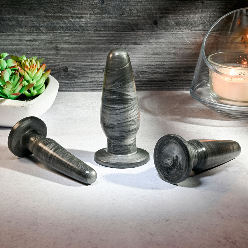 Adam & Eve ANAL ROCKETS TRAINER SET -  Butt Plugs - Set of 3 Sizes in galaxy finish on a table.