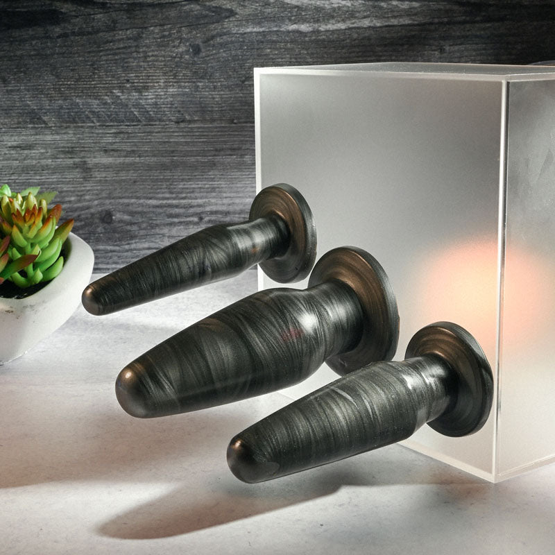 Adam & Eve ANAL ROCKETS TRAINER SET -  Butt Plugs - Set of 3 Sizes placed beside a succulent on a table.