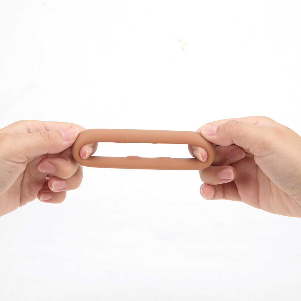 Maia GUNNER - Caramel - Tan Brown Cock Ring being held, showcasing its stretchy design for enhanced performance.