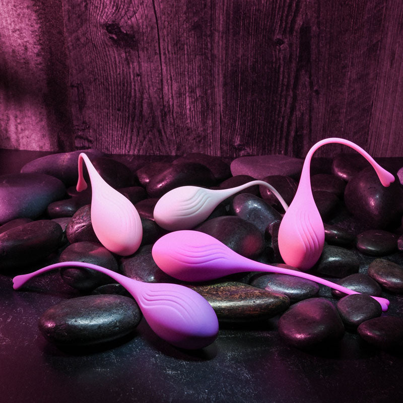 Evolved TIGHT & DELIGHT - Kegel Trainer Set - 5 Piece Kit displayed on smooth stones, enhancing intimate essentials for her.