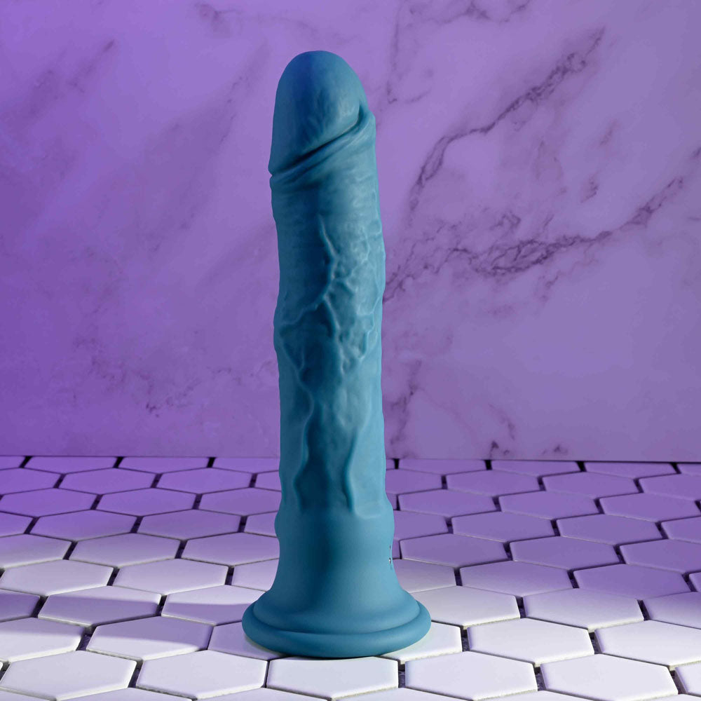 Evolved TSUNAMI -  18.4 cm USB Rechargeable Vibrating Dong with Remote Control on a hexagonal tile surface.