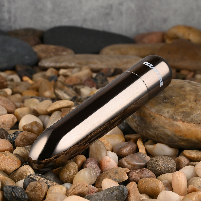 Evolved REAL SIMPLE - Black 10 cm USB Rechargeable Bullet on pebbles, showcasing its sleek design and glossy finish.