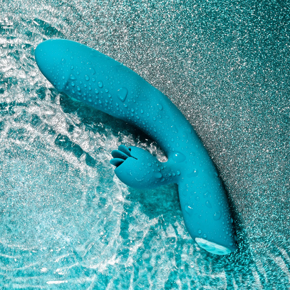 USB rechargeable rabbit vibrator submerged in water with droplets on its surface.