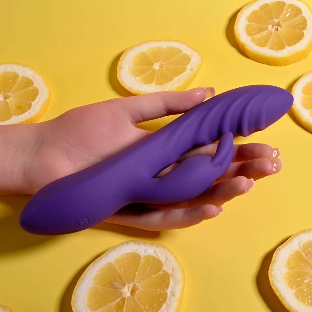 Evolved WAVY RABBIT - 20.6 cm USB Rechargeable Rabbit Vibrator held in hand with lemon slices background.