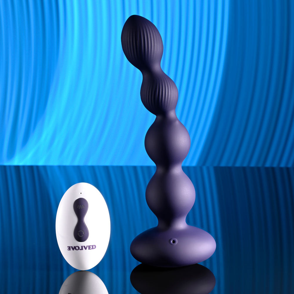 Evolved PLEASURE ORBIT - Navy  17.8 cm USB Rechargeable Twirling & Vibrating Anal Beads with Remote on a reflective surface.