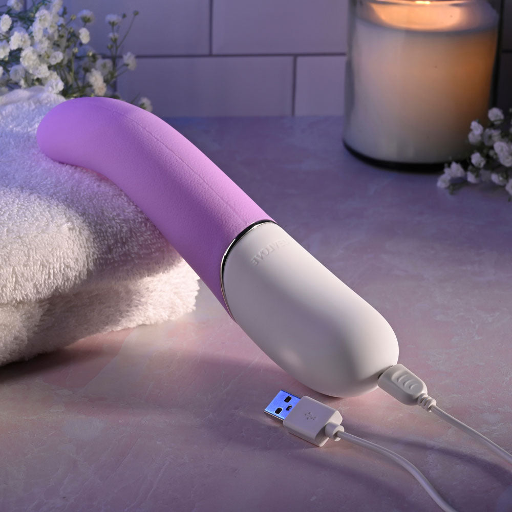 Evolved SLIP OF THE TONGUE -  21.1 cm USB Rechargeable Flicking Tongue Vibrator charging on a towel, surrounded by candles.