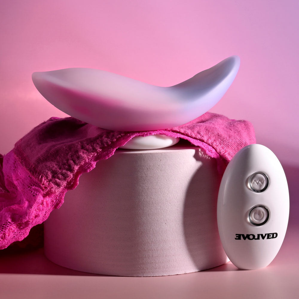 Evolved PARADISE PANTY - Pink/Purple USB Rechargeable Panty Vibrator with Remote Control on display with pink fabric.