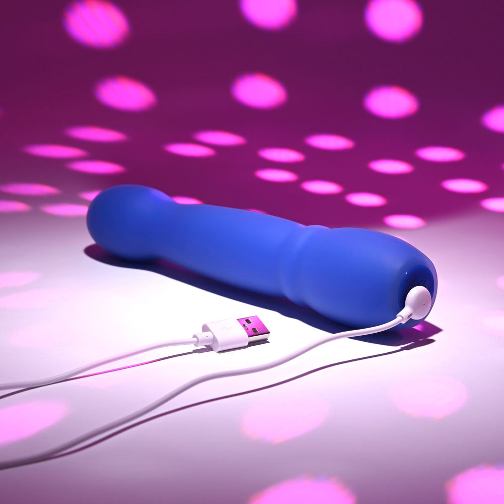Evolved DISCO DIVA -  20.9 cm USB Rechargeable Light Up Vibrator charging with colorful lights in the background.