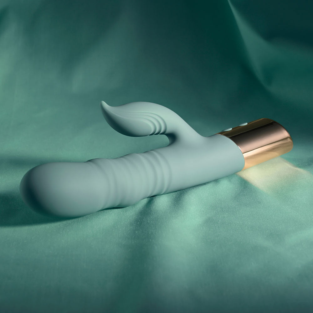 Evolved THE SHIMMY -  USB Rechargeable Thrusting Rabbit Vibrator on teal background, showcasing its sleek design.