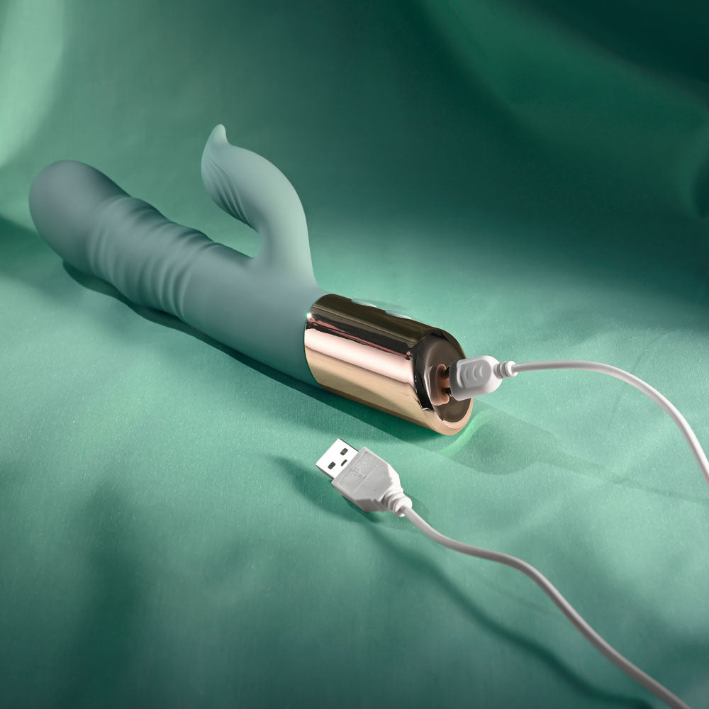 Evolved THE SHIMMY - USB Rechargeable Thrusting Rabbit Vibrator charging on a teal background.