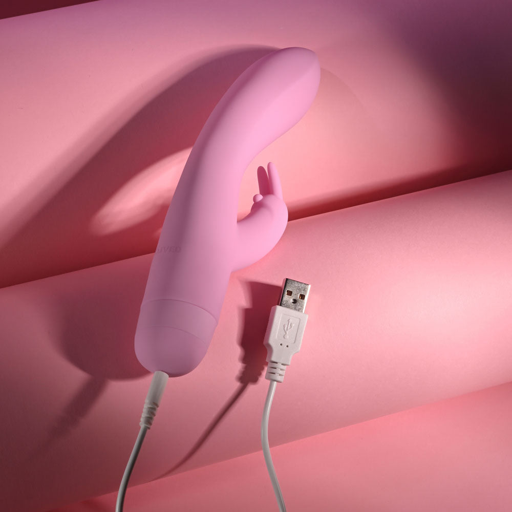 Evolved CUSHY BUNNY - 19.1 cm USB Rechargeable Rabbit Vibrator charging on pink background.