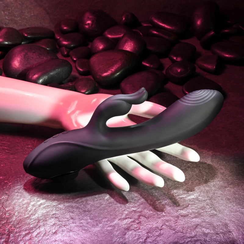 Evolved RABBIT HOLE - 21.2 cm USB Rechargeable Rabbit Vibrator positioned on a hand among smooth stones.
