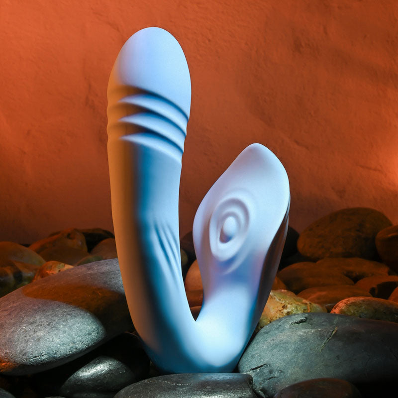 Evolved TAP & THRUST -  USB Rechargeable Dual Vibrator on smooth stones, showcasing its curved design and silky finish.