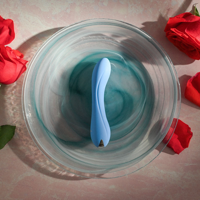 Evolved CRUSH - 12 cm USB Rechargeable Mini Vibrator in a glass bowl surrounded by red roses.