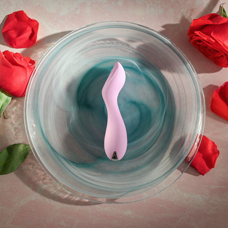 Evolved LILAC G - Lilac 11.5 cm USB Rechargeable Mini Vibrator surrounded by rose petals in a glass bowl.