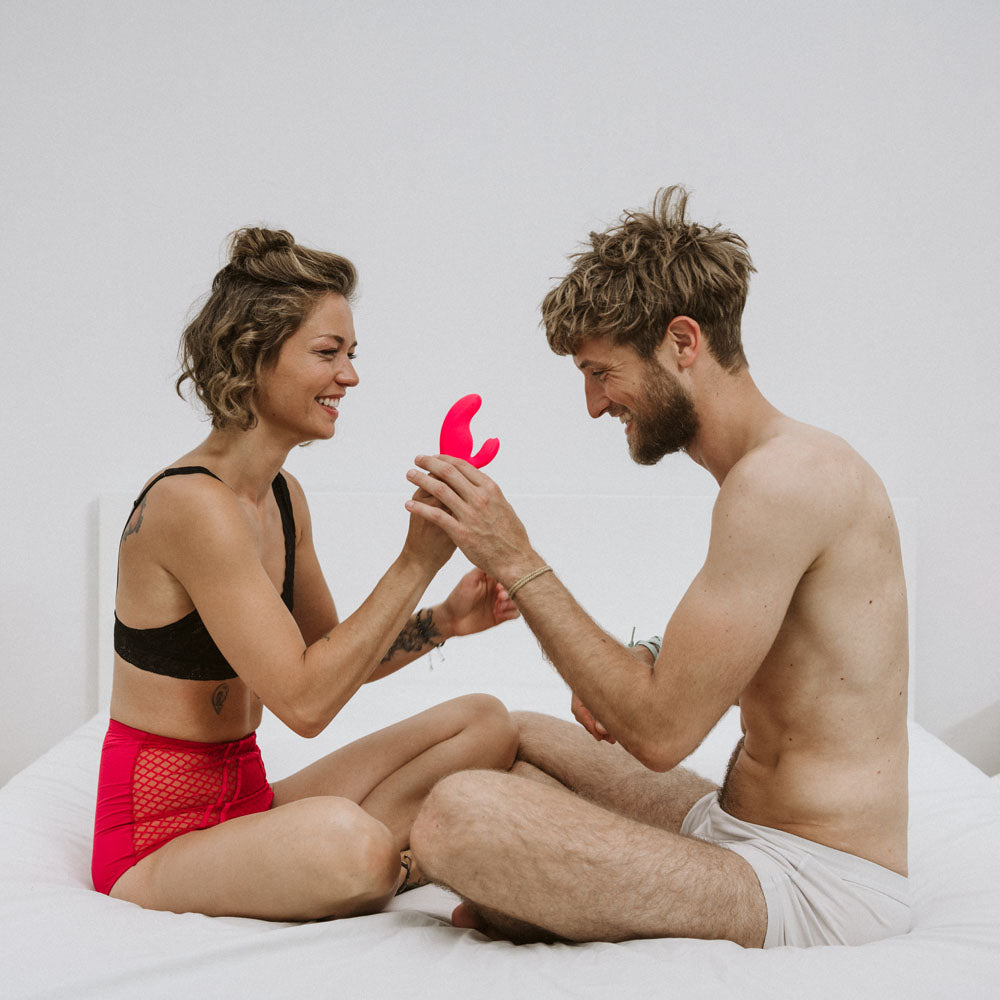 Couple exploring intimacy with the Fun Factory MISS BI - 17 cm USB Rechargeable Rabbit Vibrator in a playful setting.