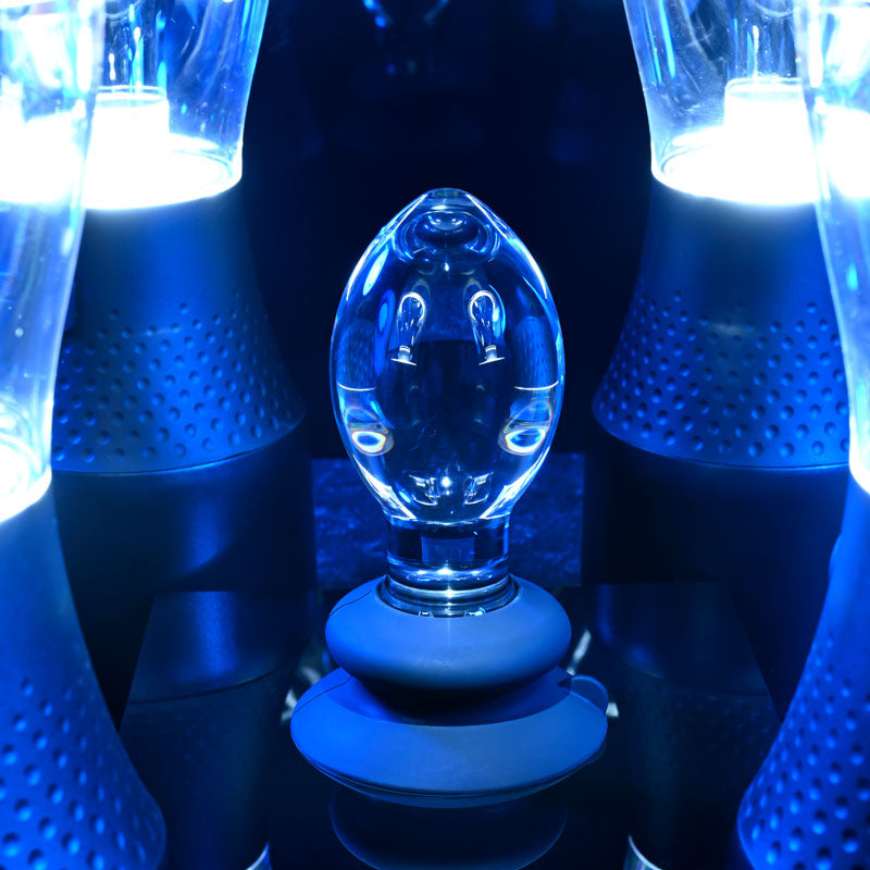 Gender X Crystal Ball -  Glass 13.6 cm Butt Plug with Suction Base illuminated by blue lights.