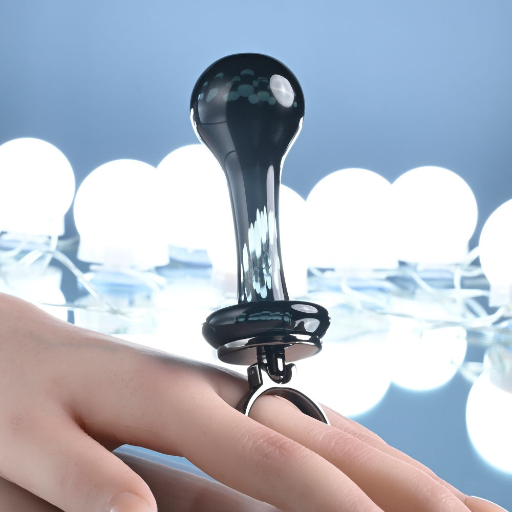Gender X BLOW POP -  12.8 cm Glass Plug with Ring Pull displayed on a hand with decorative lighting in the background.