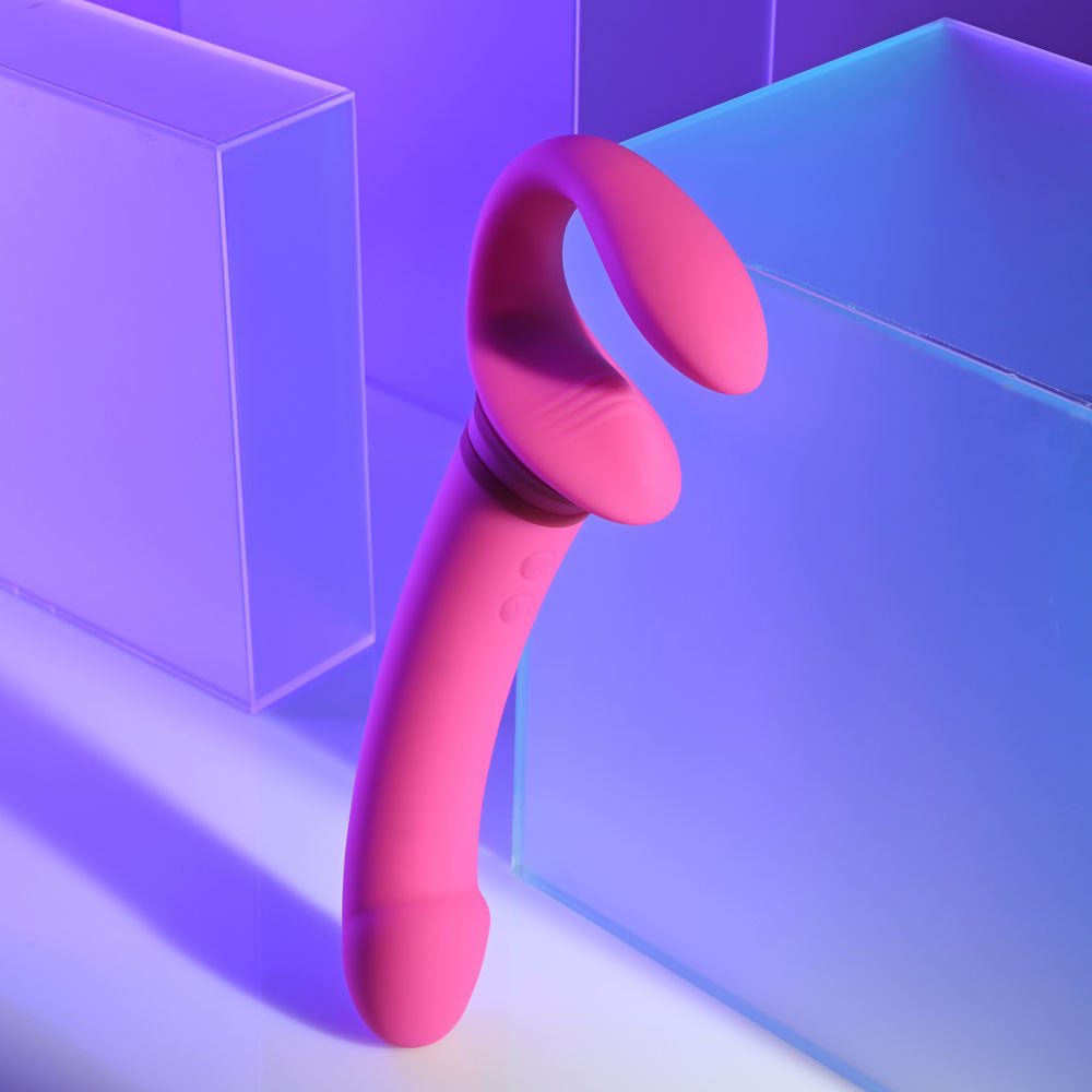Gender X SHARING IS CARING rechargeable strap-on vibrator displayed against a colorful background.