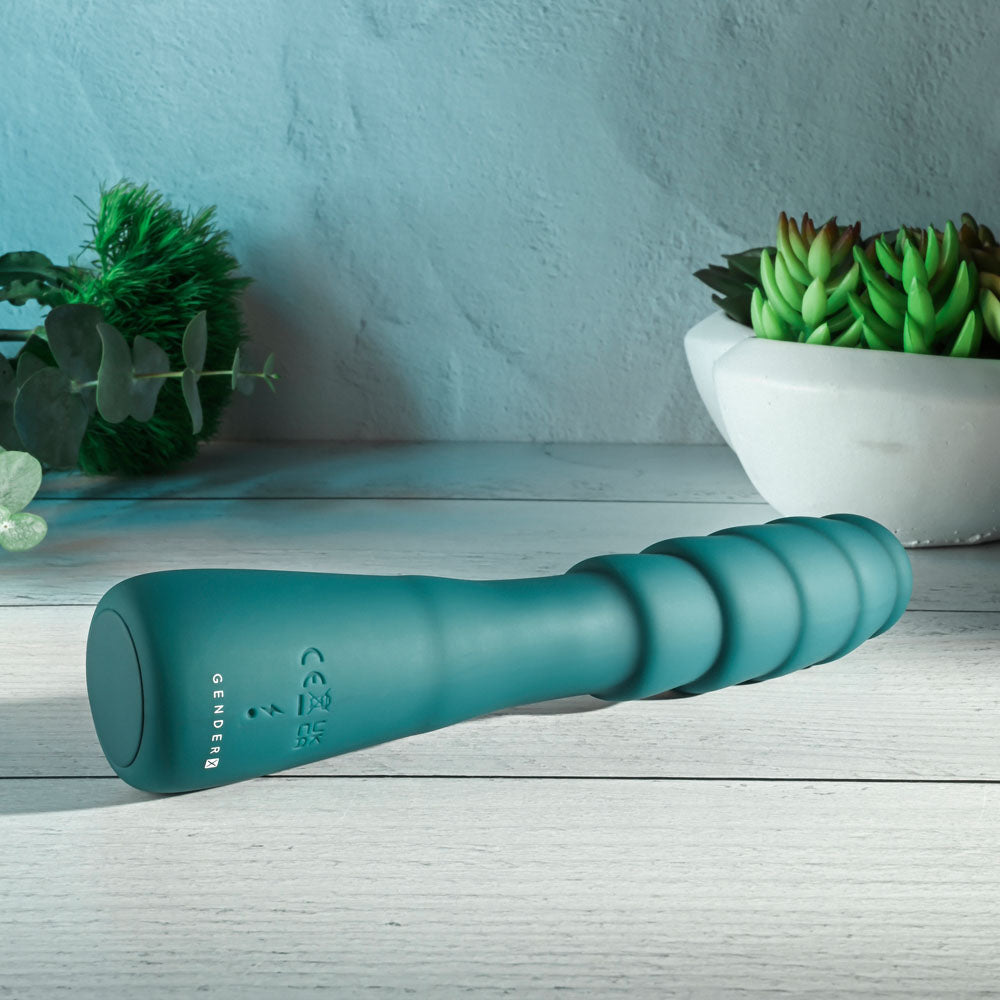 Gender X SCORPION - 21.2 cm USB Rechargeable Vibrator showcased on a wooden surface with plants.