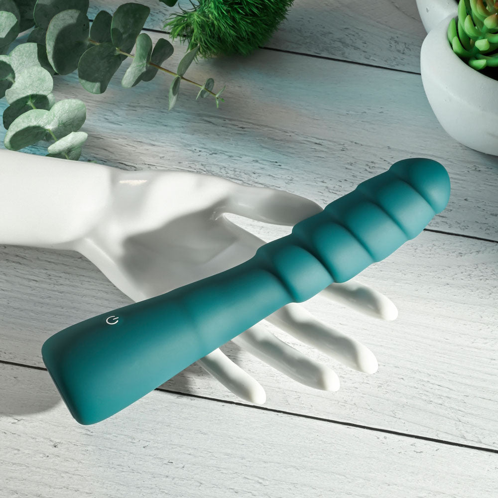 Gender X SCORPION - 21.2 cm USB Rechargeable Vibrator displayed on a hand with decorative plants in the background.