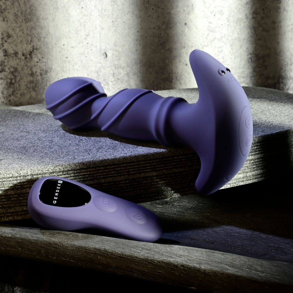 Gender X RING IT USB rechargeable vibrator with remote and ergonomic remote control on a textured surface.