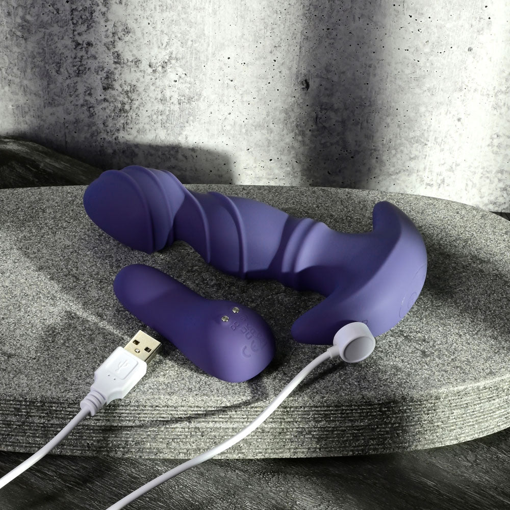 Gender X RING IT -  16.5 cm USB Rechargeable Vibrator with Wireless Remote on stone surface with USB charging cable