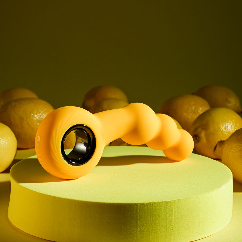 Gender X BUMBLE -  14.9 cm USB Rechargeable Butt Plug on a vibrant green surface surrounded by lemons.