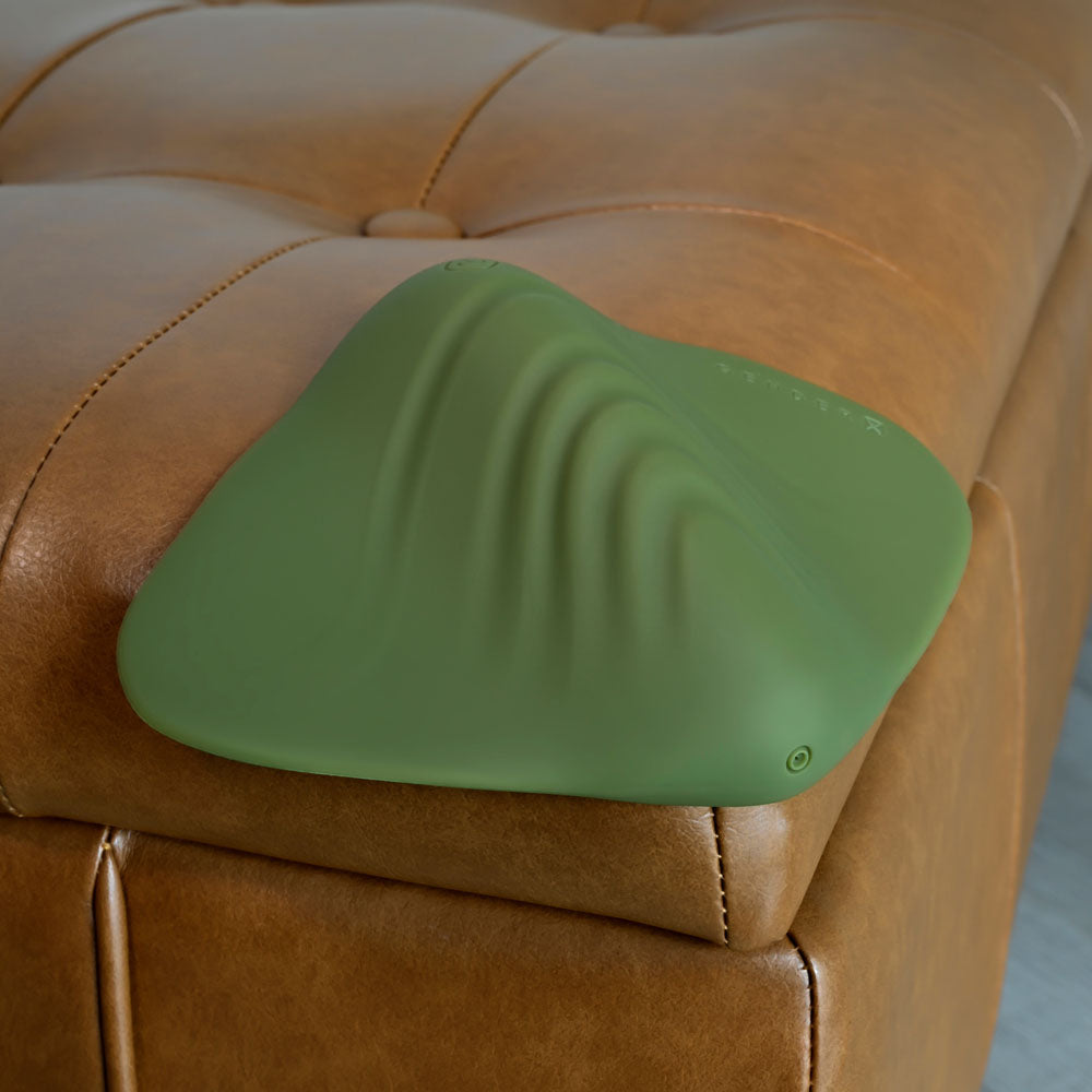 Gender X PLEASURE PAD -  USB Rechargeable Grinding Pad resting on a leather couch, showcasing its soft and flexible design.