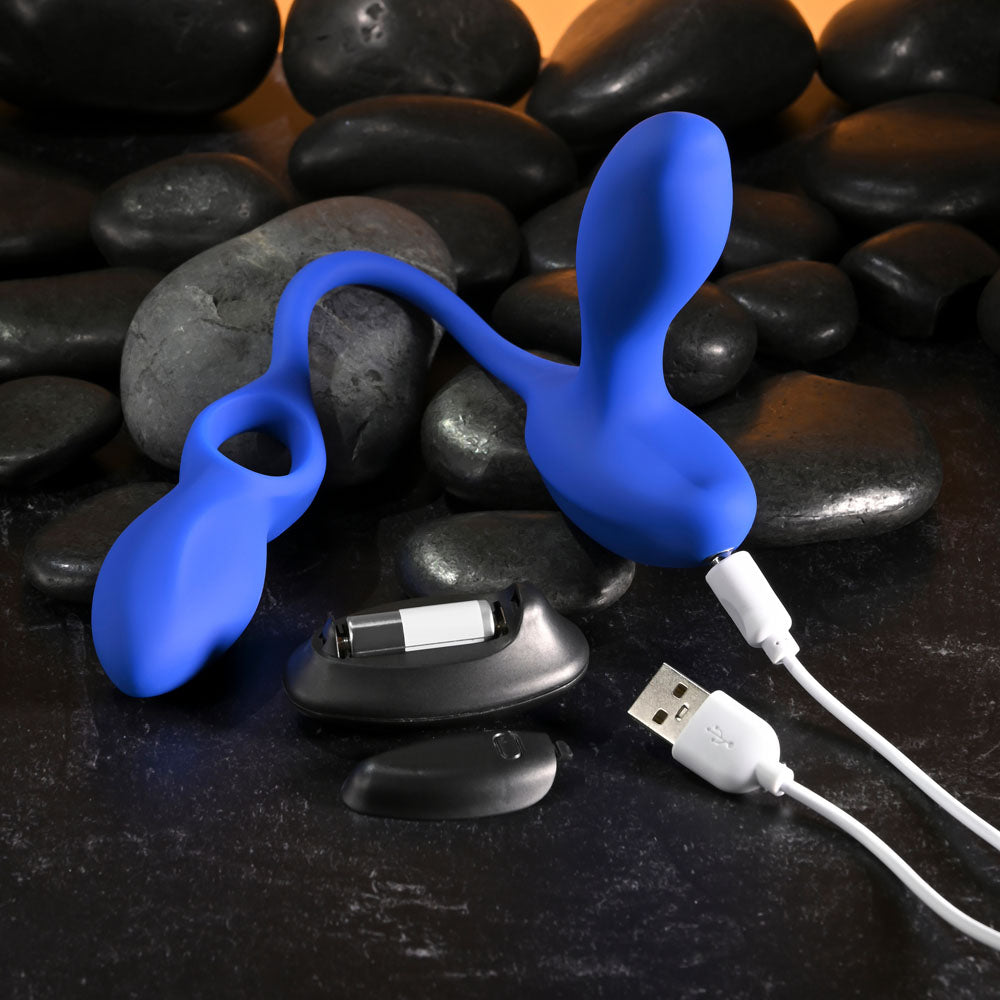 Gender X BACK FOR MORE - Dual USB Rechargeable Dual Stimulator with Wireless Remote on rocks with charging cable.