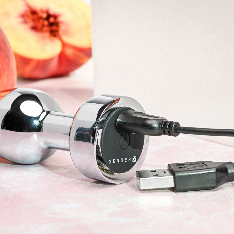 Gender X ROCKIN' METAL PLUG - Metallic 9.3 cm USB Rechargeable Butt Plug charging on a pink surface.