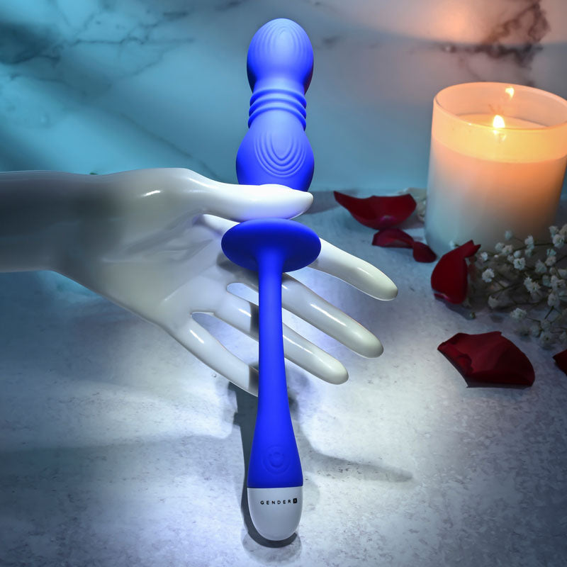 Gender X rechargeable vibrating orbs on a hand, featuring a sleek design and soft blue silicone finish, surrounded by candlelight.