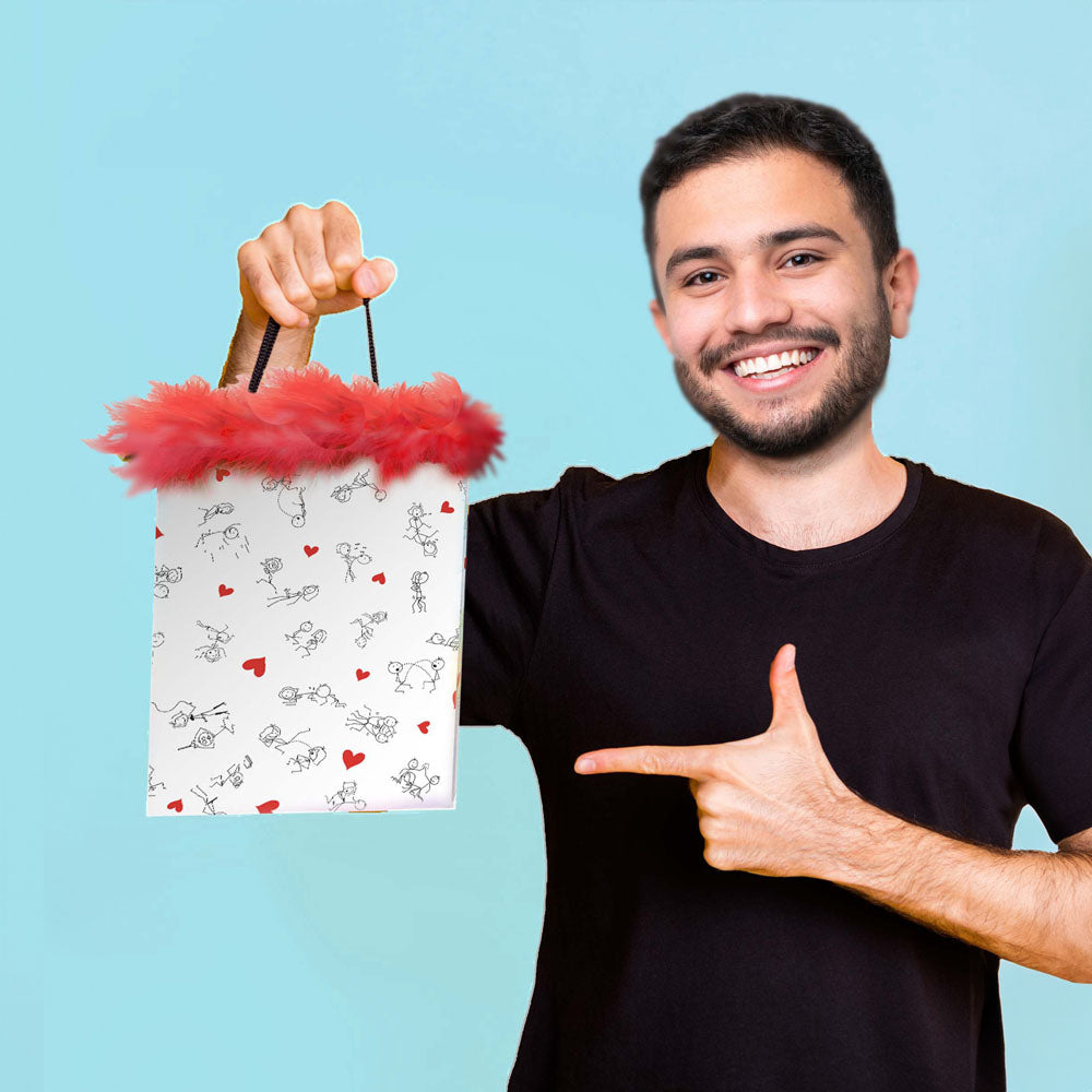 Smiling man holding the Naughty Stick Figures Gift Bag - Novelty Gift Bag with marabou fringe, showcasing its humorous design.